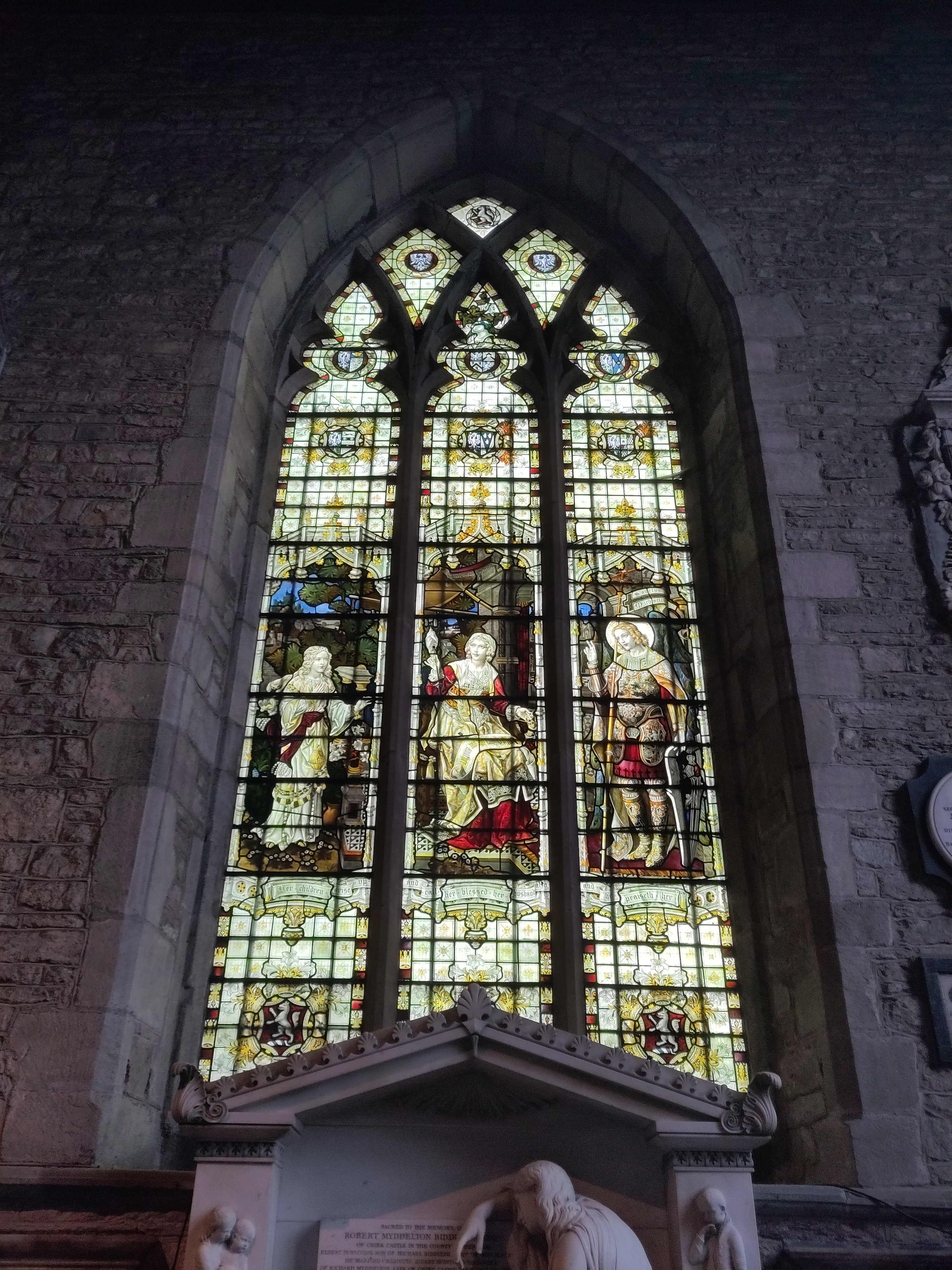 A photograph of the entire window. You can see heraldry in the traceries above the figures and faint inscriptions below.